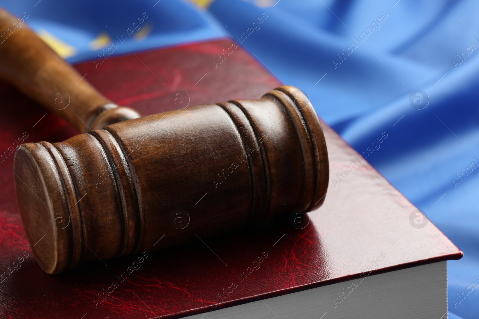 Photo of Wooden judge's gavel and book on blue fabric, closeup