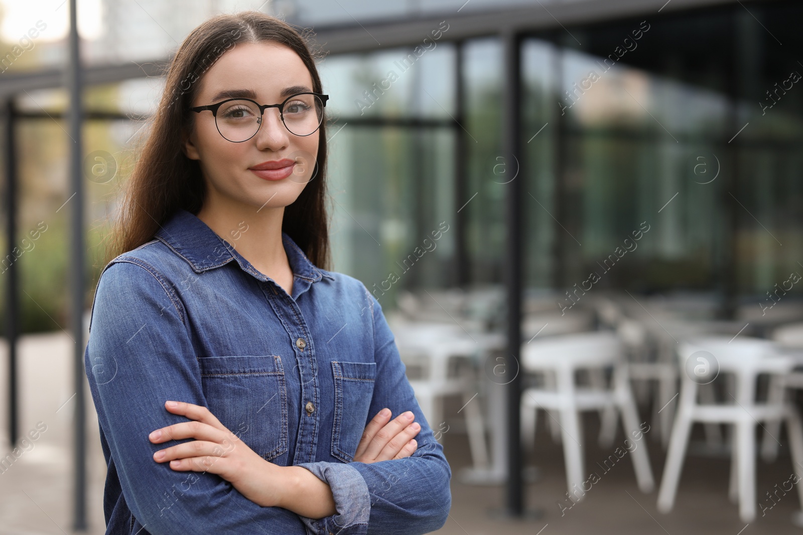 Photo of Portrait of beautiful woman in glasses with crossed arms outdoors. Attractive lady posing for camera. Space for text