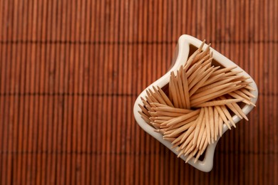 Photo of Holder with many toothpicks on bamboo mat, top view. Space for text