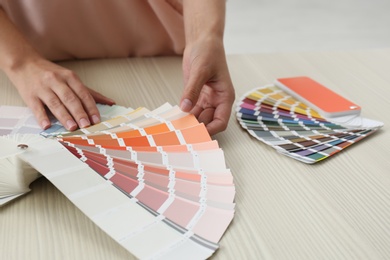 Photo of Female interior designer with color palette samples at wooden table, closeup