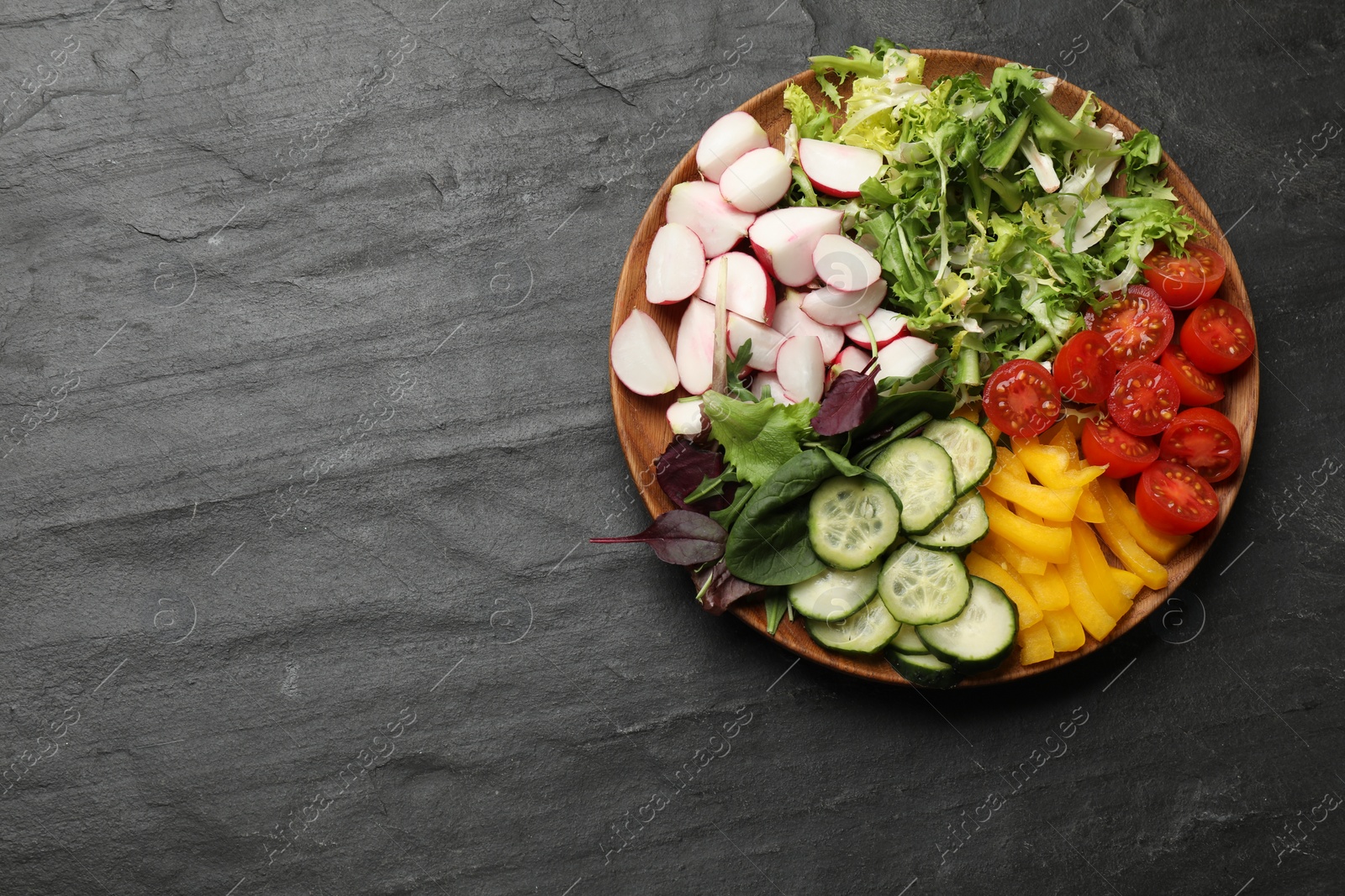 Photo of Vegetarian diet. Plate with tasty vegetables on black table, top view. Space for text