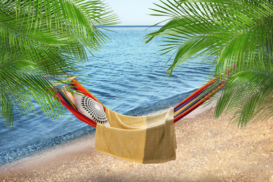 Image of Hammock between palms at sandy beach near sea on sunny day