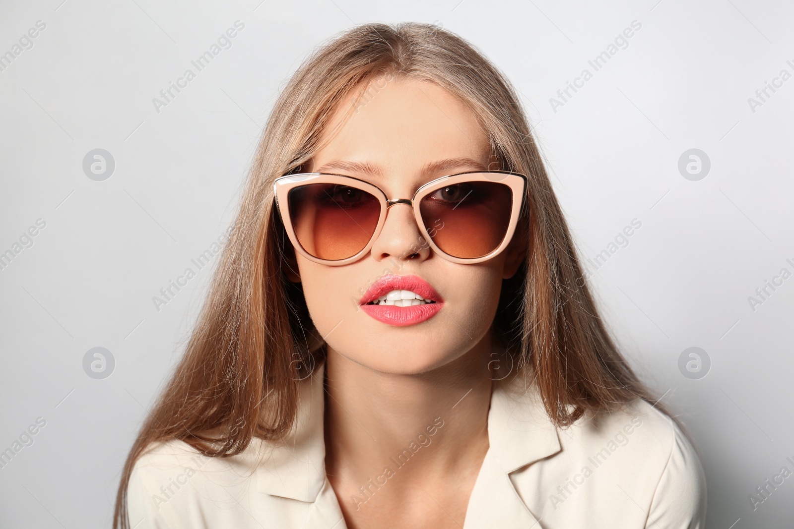 Photo of Young woman wearing stylish sunglasses on light background