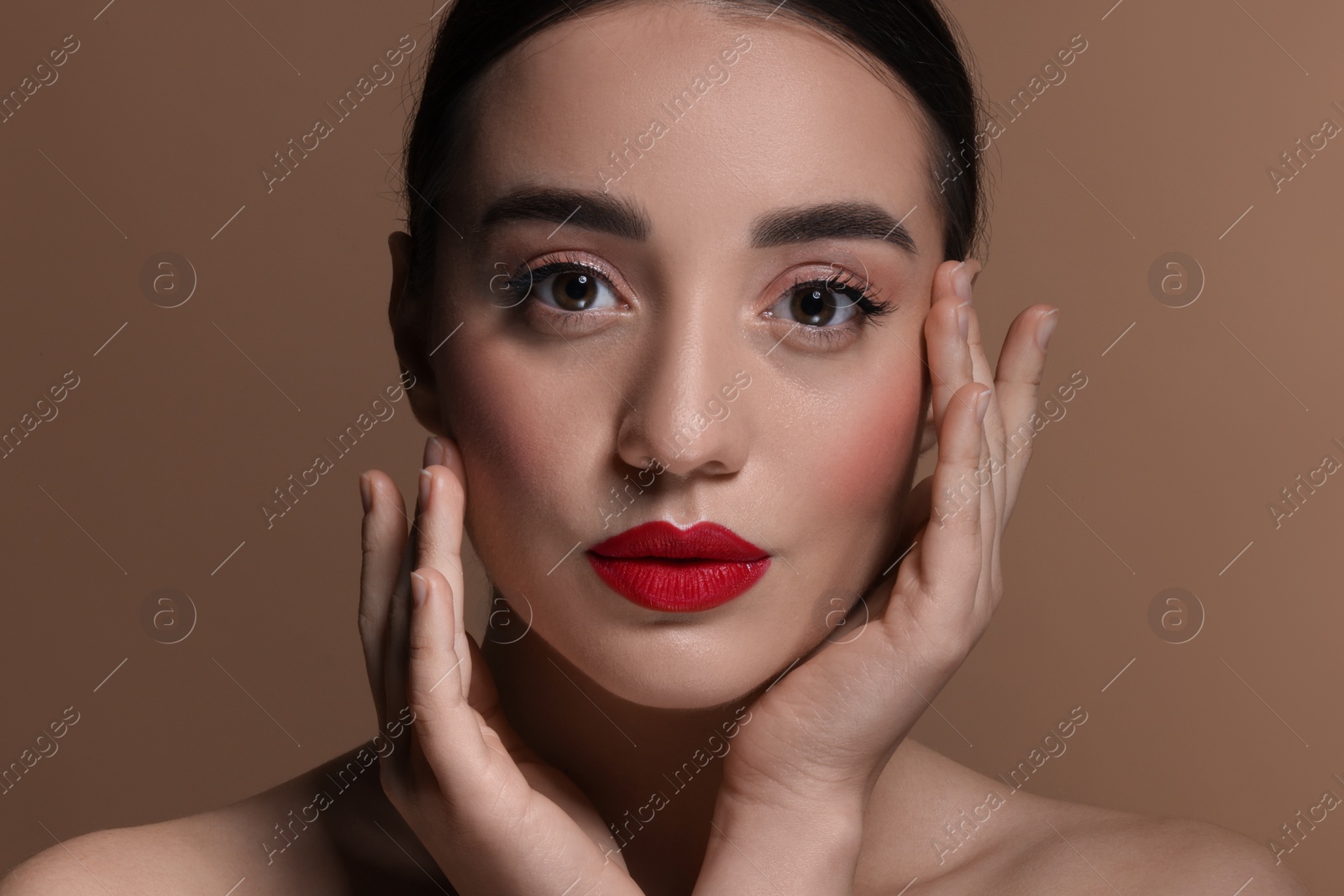 Photo of Portrait of beautiful young woman with red lips on brown background, closeup