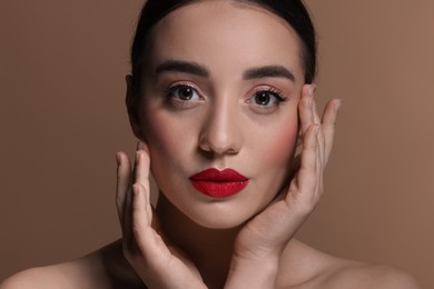 Portrait of beautiful young woman with red lips on brown background, closeup