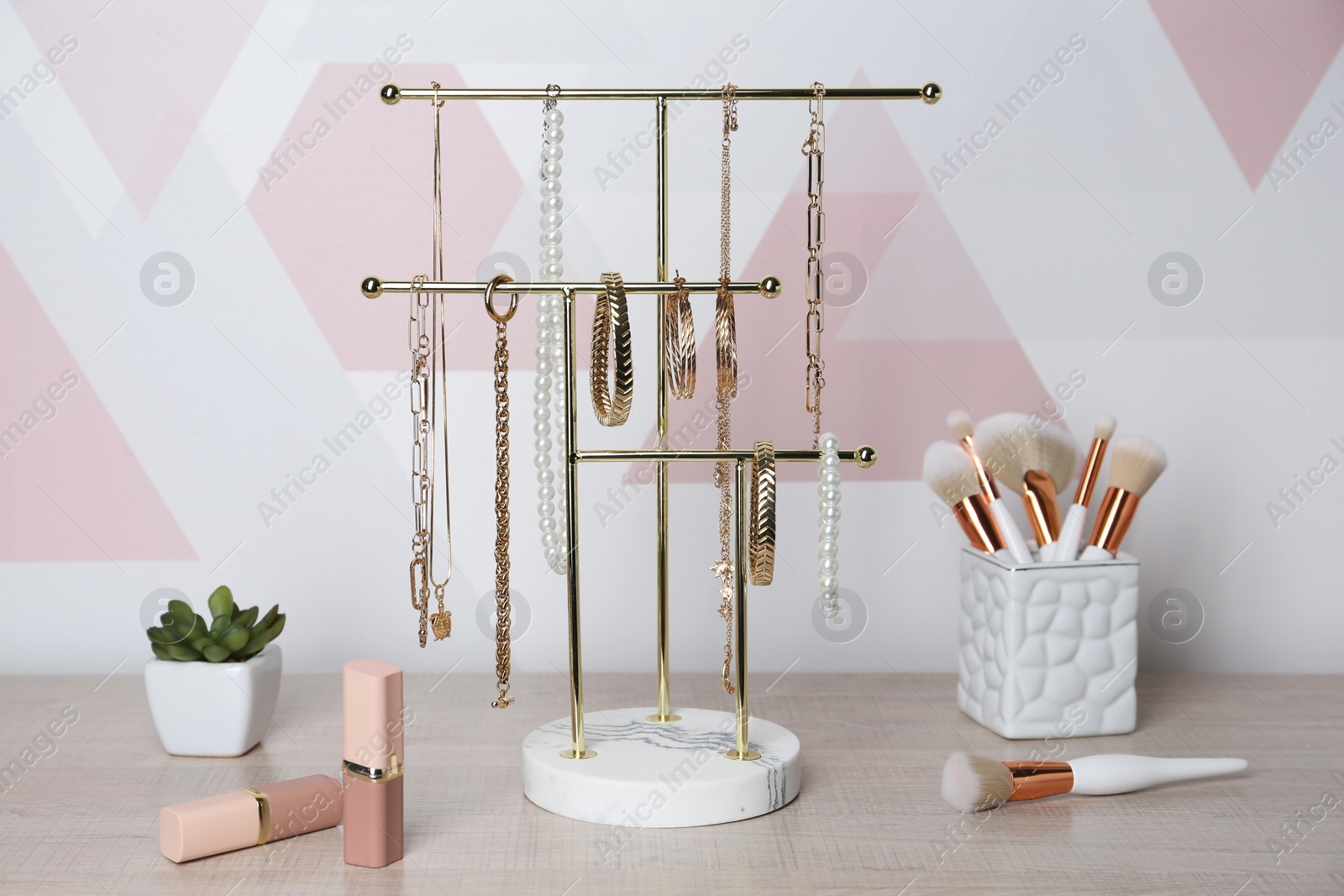 Photo of Holder with set of luxurious jewelry on wooden dressing table