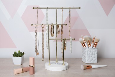 Photo of Holder with set of luxurious jewelry on wooden dressing table