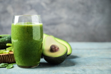 Delicious green juice and fresh ingredients on light blue wooden table, space for text