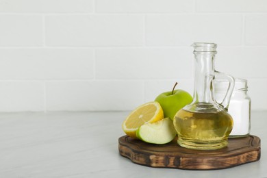 Photo of Vinegar and fresh fruits on white marble table, space for text. Eco friendly natural detergents