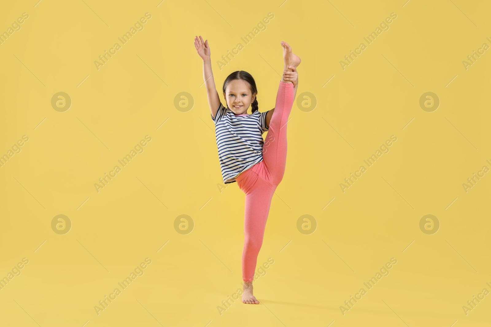 Photo of Cute little girl stretching on yellow background