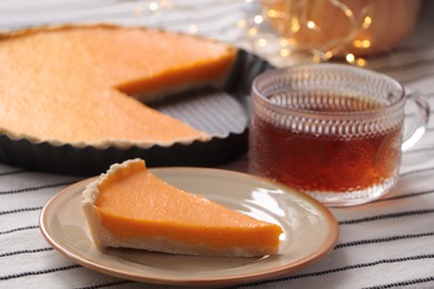 Photo of Piece of fresh homemade pumpkin pie served with tea on table