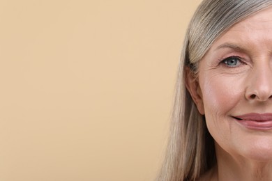 Photo of Portrait of beautiful senior woman on beige background, closeup. Space for text