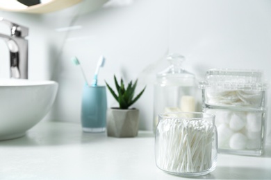 Jar with cotton swabs on white countertop in bathroom