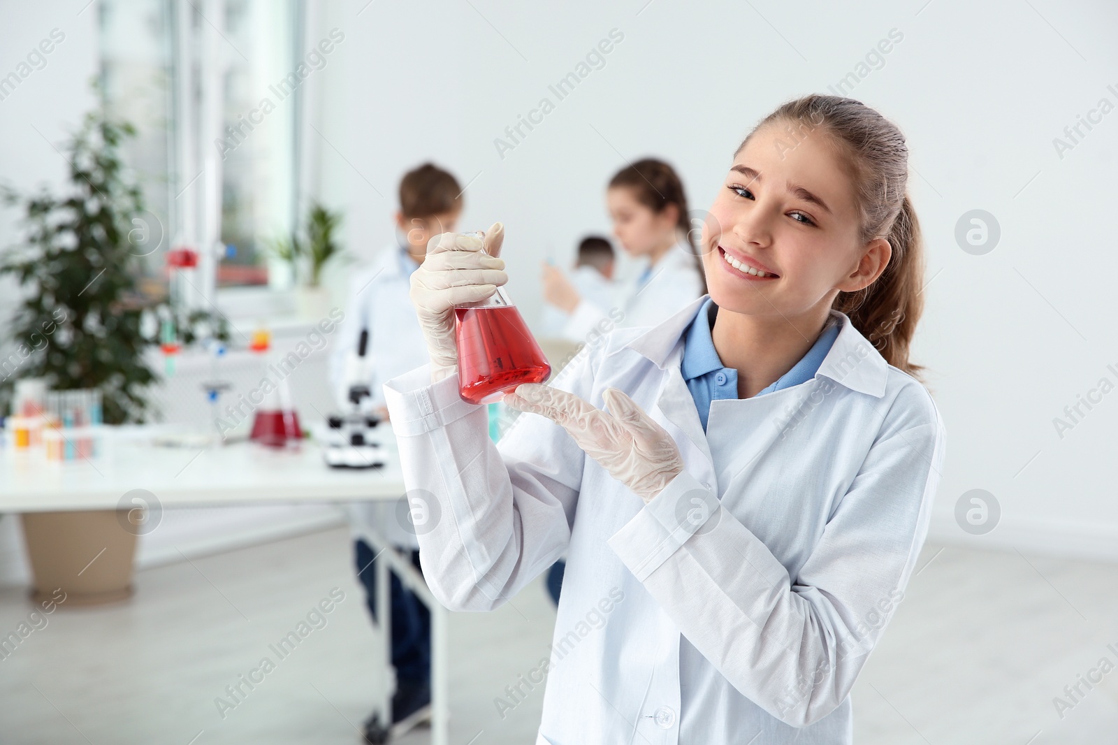 Photo of Schoolgirl holding conical flask at chemistry class