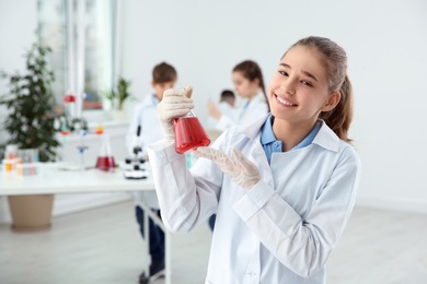 Schoolgirl holding conical flask at chemistry class
