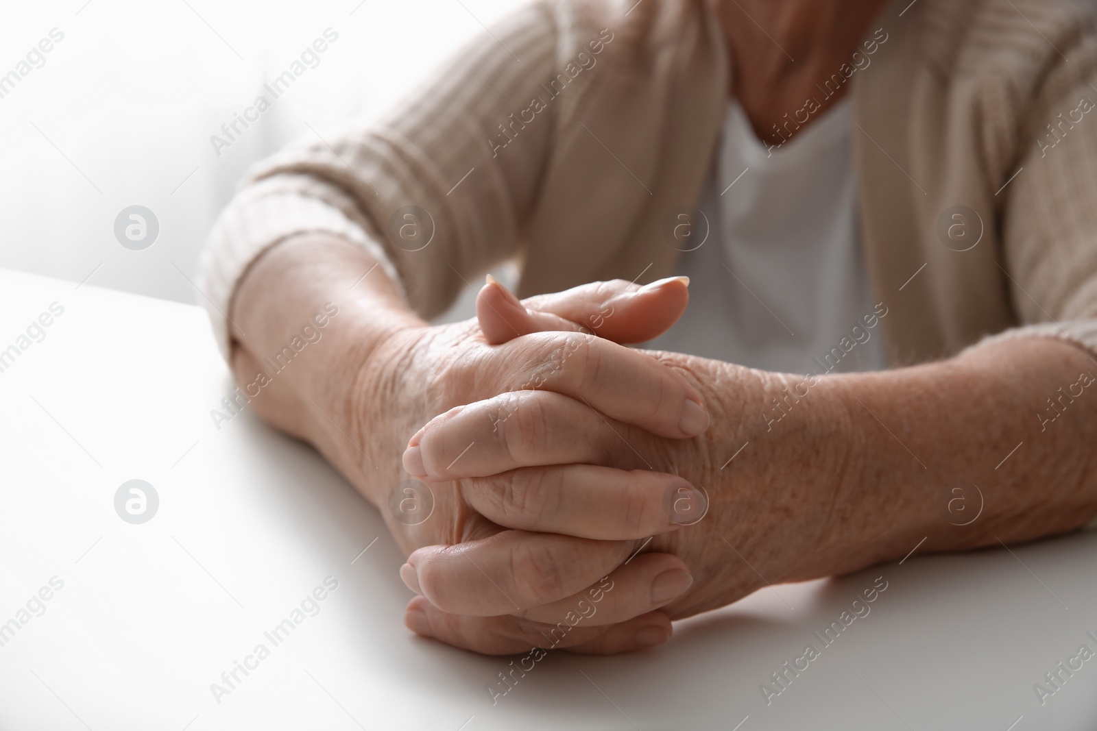 Photo of Elderly woman at white table, closeup view