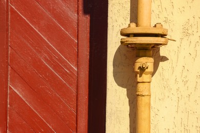 Photo of Yellow gas pipe on beige wall outdoors