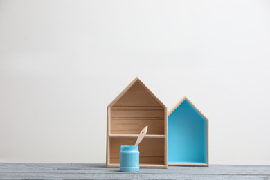 Photo of Brush with paint and wooden houses on grey table