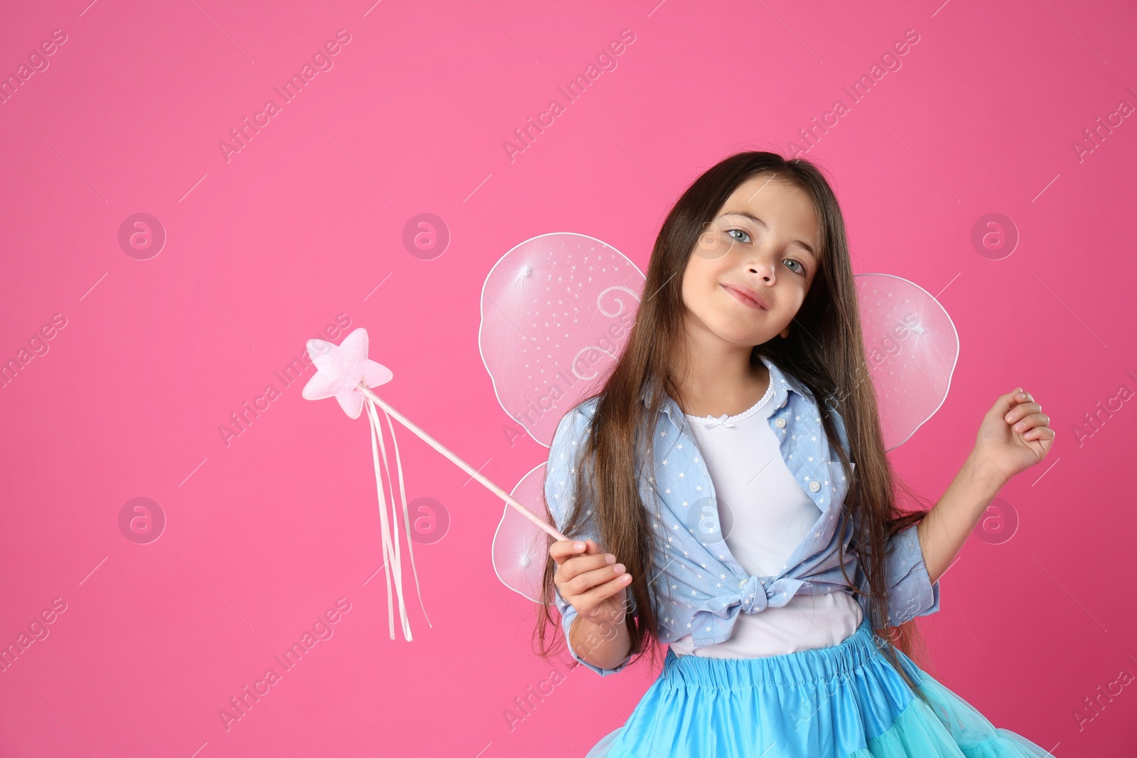 Photo of Cute little girl in fairy costume with wings and magic wand on pink background