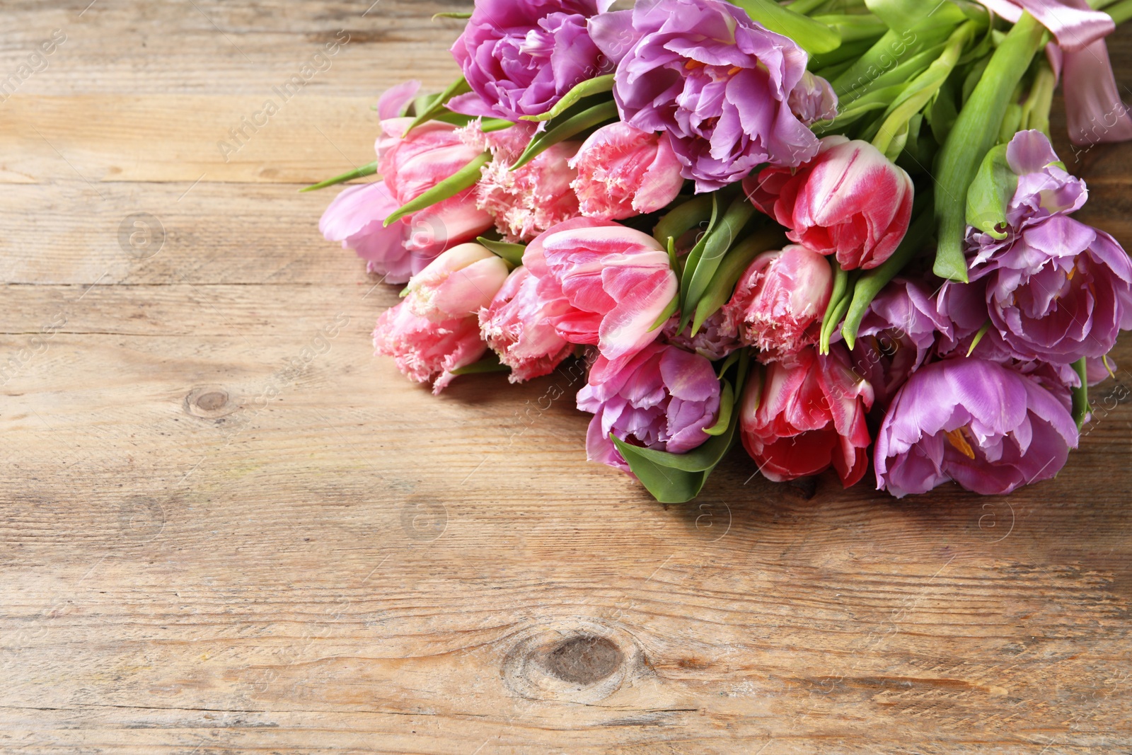 Photo of Beautiful bouquet of colorful tulip flowers on wooden table