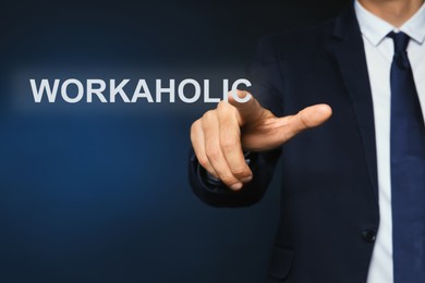 Image of Man pointing at word Workaholic on virtual screen against dark background