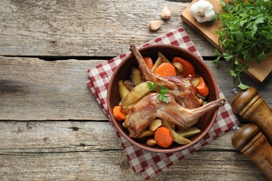 Photo of Tasty cooked rabbit with vegetables served on wooden table, flat lay. Space for text