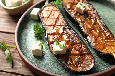 Plate with fried eggplant slices on wooden table, closeup