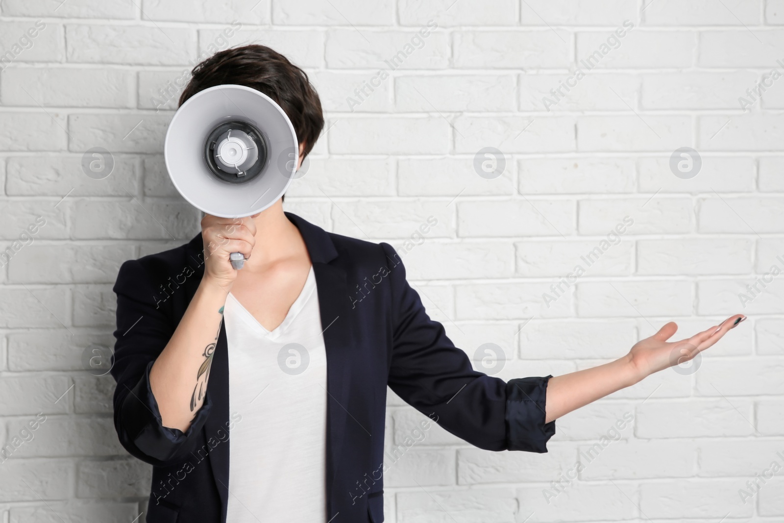 Photo of Young woman with megaphone on brick wall background