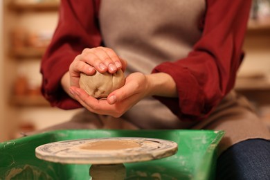 Photo of Woman crafting with clay over potter's wheel indoors, closeup