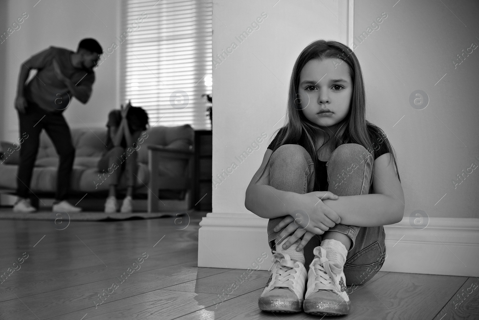 Image of Couple fighting at home, focus on their unhappy little daughter. Domestic violence