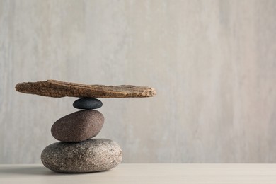 Photo of Stack of stones with tree branch on wooden table, space for text. Harmony and balance concept