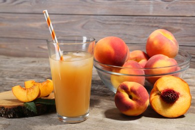 Photo of Glass of delicious peach juice with ice and fresh fruits on wooden table