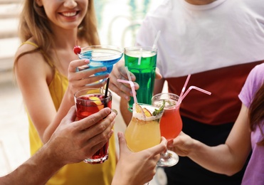 Photo of Friends clinking glasses with fresh summer cocktails outdoors, closeup