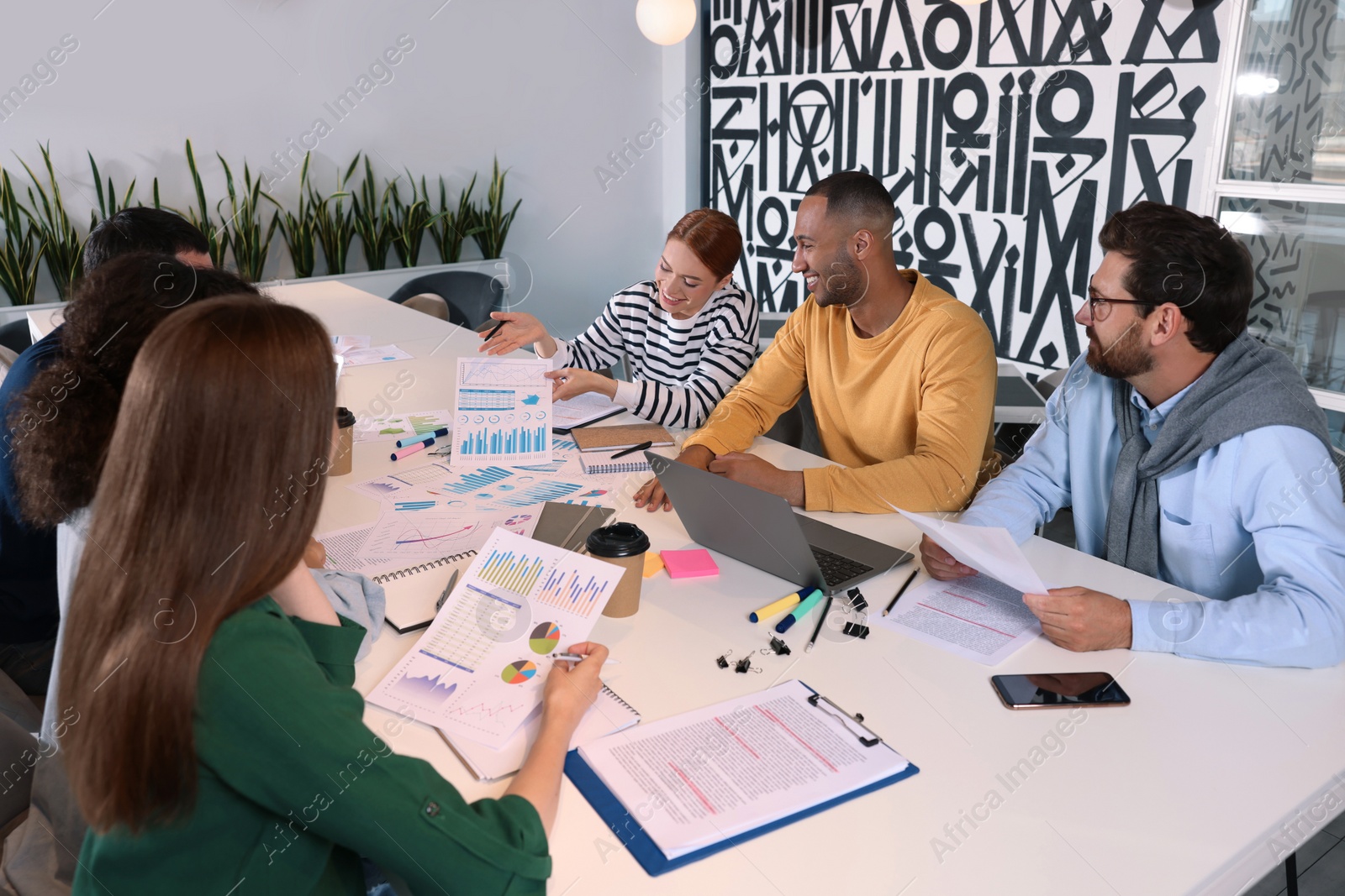 Photo of Team of employees working together at table in office. Startup project