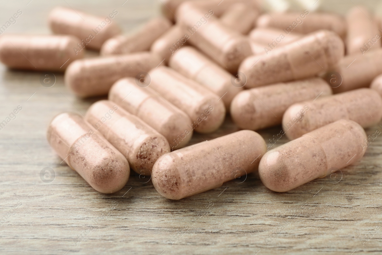 Photo of Gelatin capsules on wooden table, closeup view