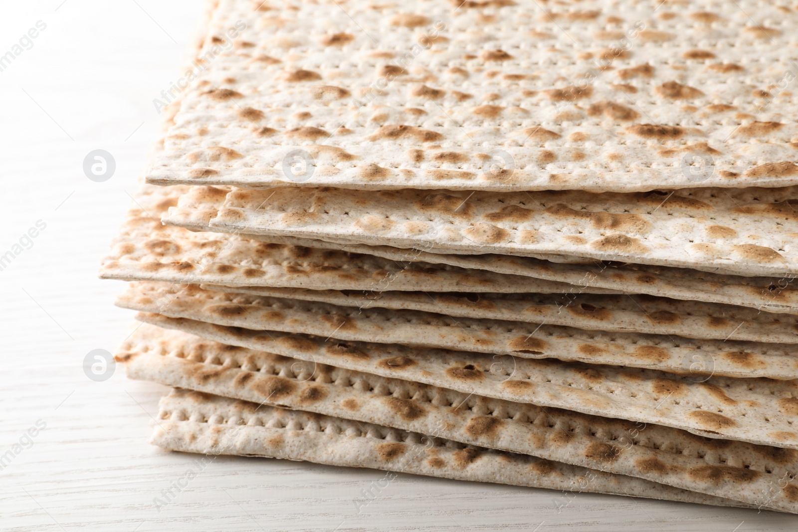 Photo of Stack of matzos on white wooden table, closeup