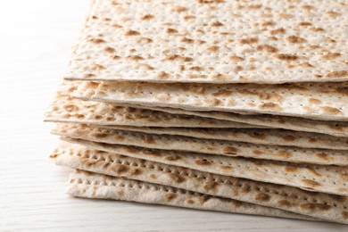 Photo of Stack of matzos on white wooden table, closeup