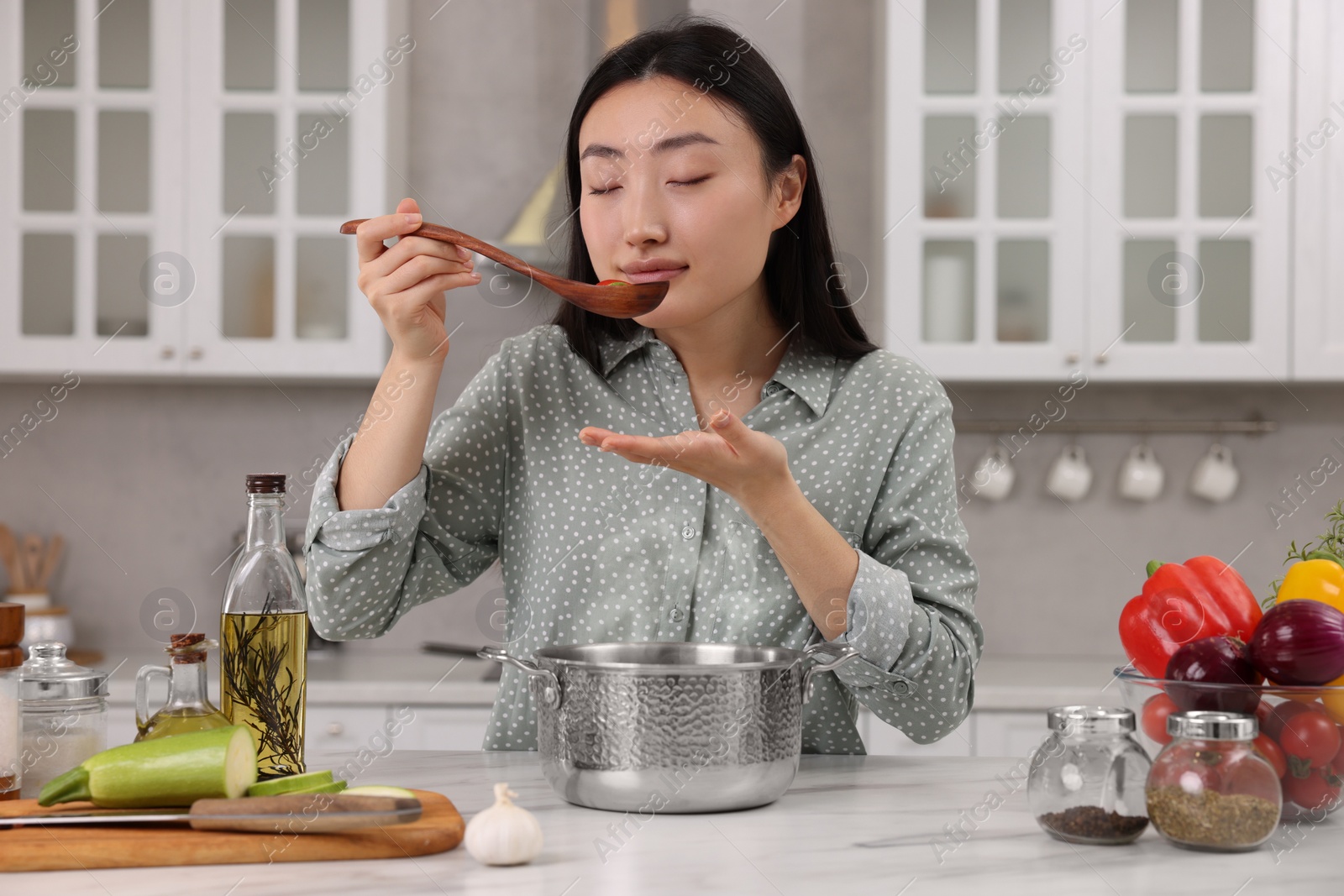 Photo of Beautiful woman tasting food after cooking in kitchen