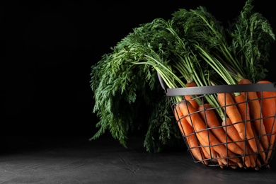 Basket with raw carrots on grey table