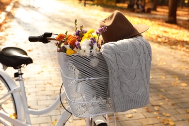 Modern bicycle with basket full of flowers in autumn park