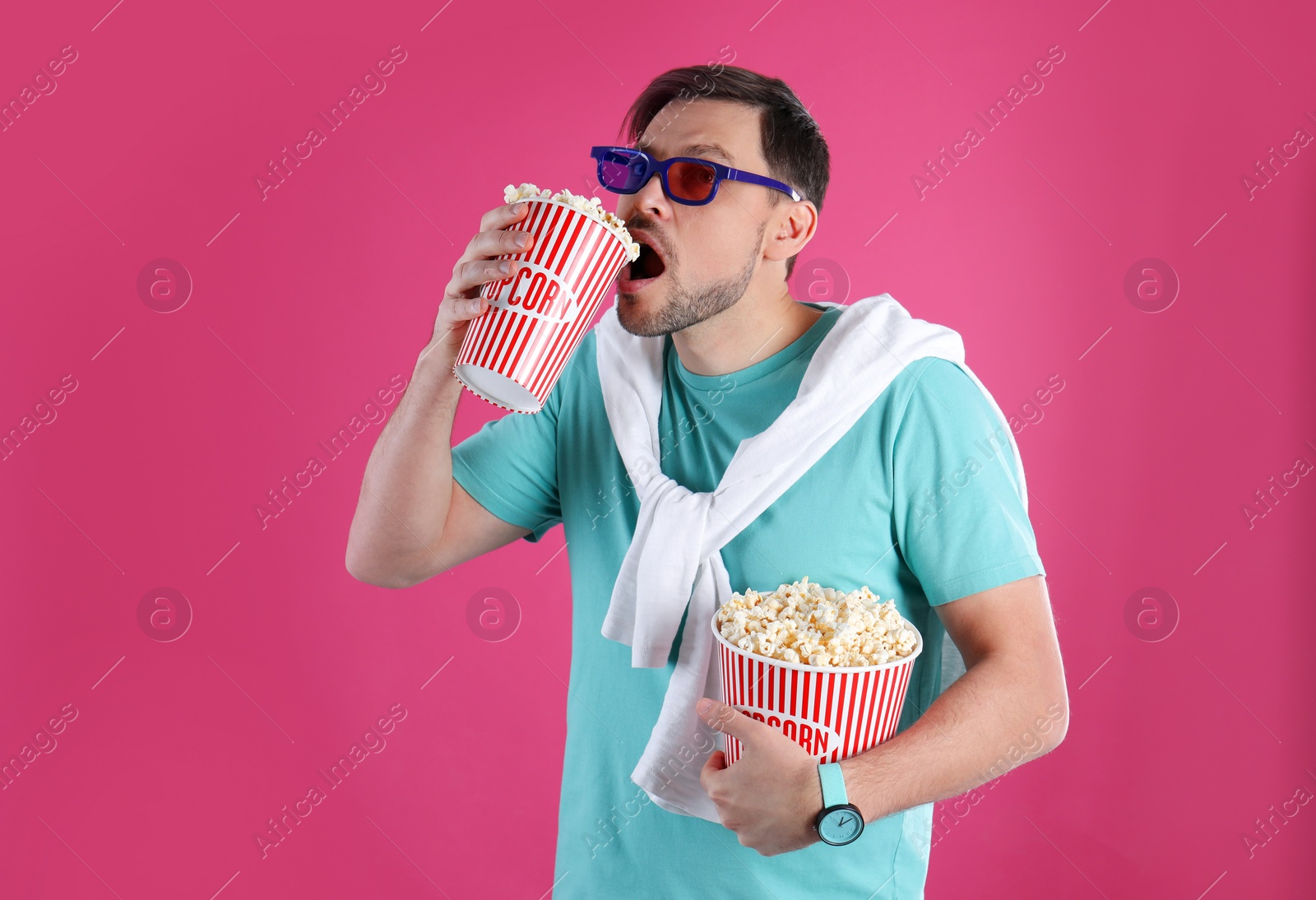 Photo of Man with 3D glasses eating tasty popcorn on color background