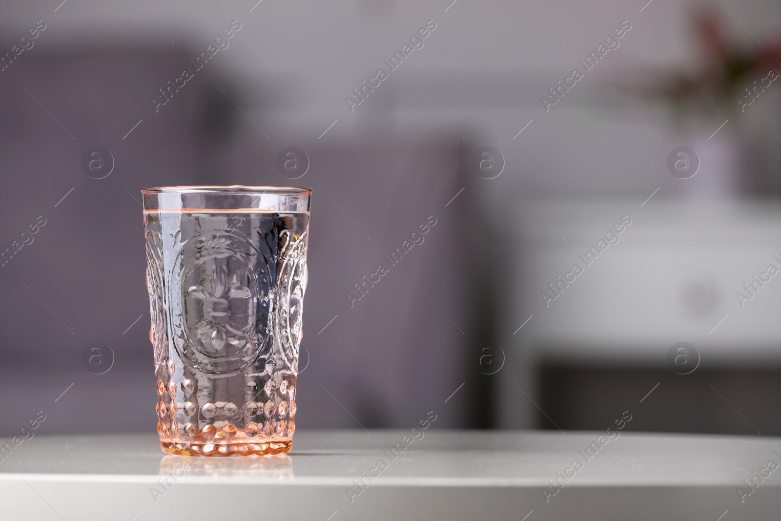 Photo of Glass of clean water on white table indoors, space for text