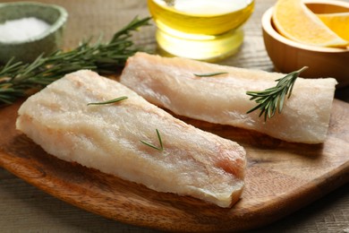 Fresh raw cod fillets, spices and lemon on wooden table, closeup