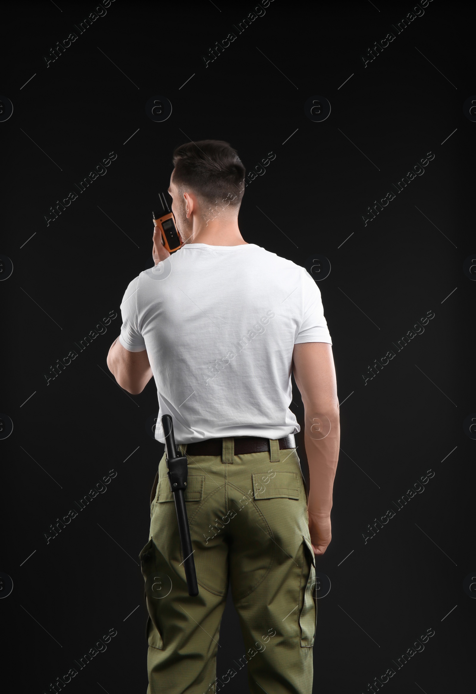 Photo of Male security guard using portable radio transmitter on dark background