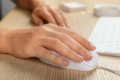 Photo of Woman using wired computer mouse at wooden table, closeup