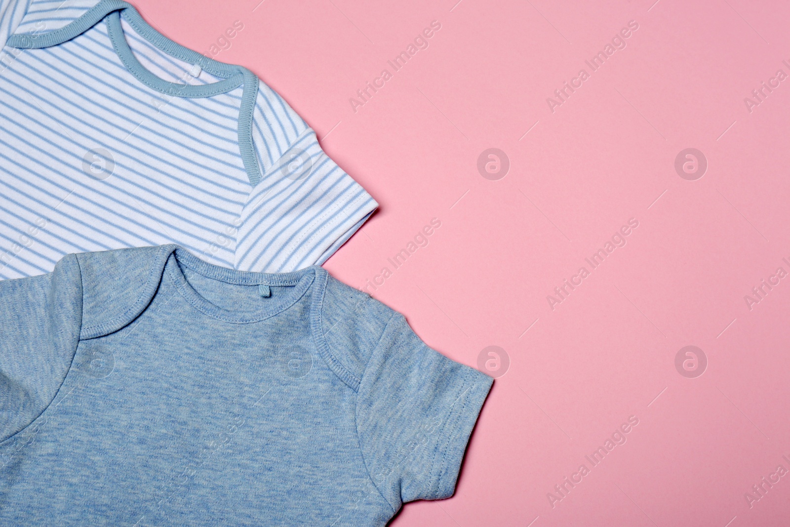 Photo of Cute baby onesies on color background, top view. Space for text