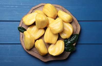 Photo of Delicious exotic jackfruit bulbs on blue wooden table, top view