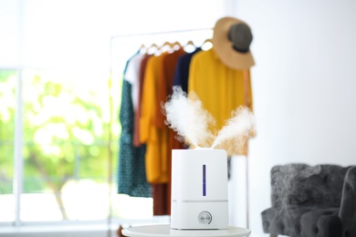 Photo of Modern air humidifier on table indoors. Space for text