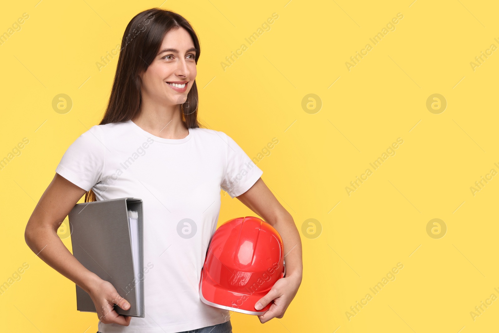 Photo of Architect with hard hat and folder on yellow background, space for text