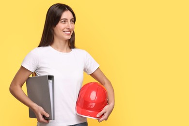 Photo of Architect with hard hat and folder on yellow background, space for text